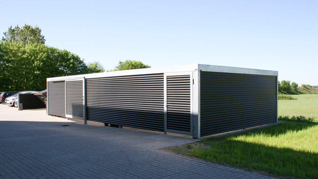 UNA teknikrum med skydedør og forlængelse til containergård. Beklædt med sinusplader.