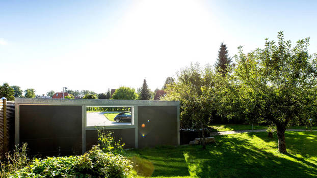 UNA garage med beklædning i Isopanel og vindue. Garagen set fra havesiden