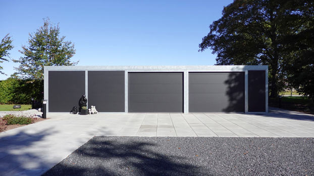 Stor UNA garage med plads til 2 biler og tilhørende skur. I tagrenderne er der tagrendenet